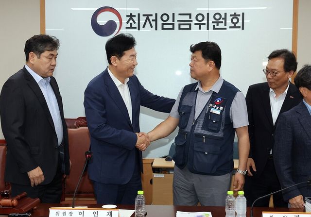 최저임금위원회 사용자위원 운영위원인 류기정 한국경영자총협회 전무(왼쪽)와 근로자위원 운영위원인 류기섭 한국노총 사무총장이 10일 정부세종청사에서 열린 제12차 전원회의에서 내년&nbsp;최저임금을 시간당 1만320원으로 17년 만에 합의로 결정한 뒤 악수하고 있다. 왼쪽은 이인재 위원장, 오른쪽은 이명로 중소기업중앙회 인력정책본부장.&nbsp; 사진/연합뉴스