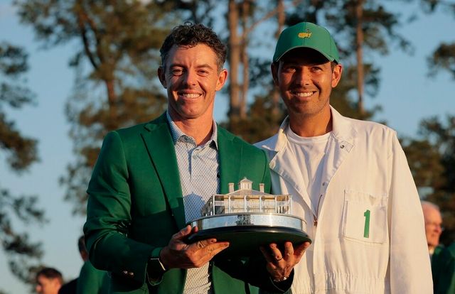 매킬로이(왼쪽)가 그린 자켓을 입고 캐디와 함께 세리머니하고 있다. /연합뉴스