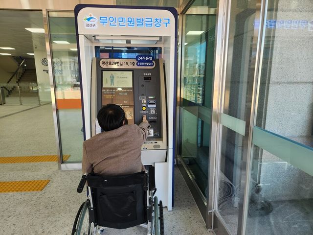 휠체어 장애인이 기능이 개선된 무인민원 발급기를 이용하고 있다.
