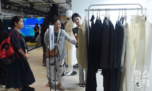 한국패션산업협회가 22일 서울 강남구 코엑스 더 플라츠에서 국내 최대 규모의 B2B 패션 수주 전시회인 'K-패션 커넥트'을 연 가운데 방문객들이 October Second 부스서 의상을 살펴보고 있다./ 이호형 기자 leemario@sporbiz.co.kr 2026.07.22