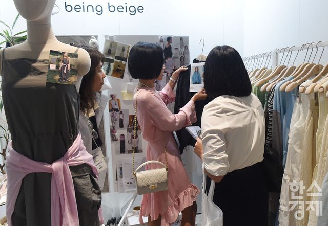 한국패션산업협회가 22일 서울 강남구 코엑스 더 플라츠에서 국내 최대 규모의 B2B 패션 수주 전시회인 'K-패션 커넥트'을 연 가운데 방문객들이 Arts De Base 부스서 의상을 살펴보고 있다./ 이호형 기자 leemario@sporbiz.co.kr 2026.07.22