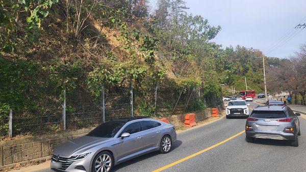 지난 7월부터 약 4개월간 방치돼 있던 매몰 토사로 낙석 방지 펜스가 내려 앉은 가운데 방문객 차량이 해당 구간을 지나고 있다. 독자 제공