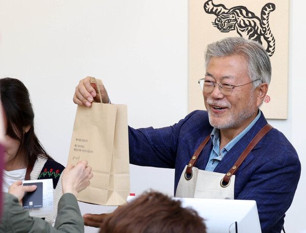 문재인&nbsp;전 대통령이 26일 오후 경남 양산시 하북면 자신의 책방 '평산책방'에서 계산 업무를 하며 책을 손님에게 건네고 있다. [연합뉴스]