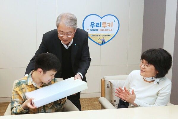 임종룡 우리금융그룹 회장(가운데)이 초청 가족에게 선물을 전달하고 있다. [우리금융그룹]