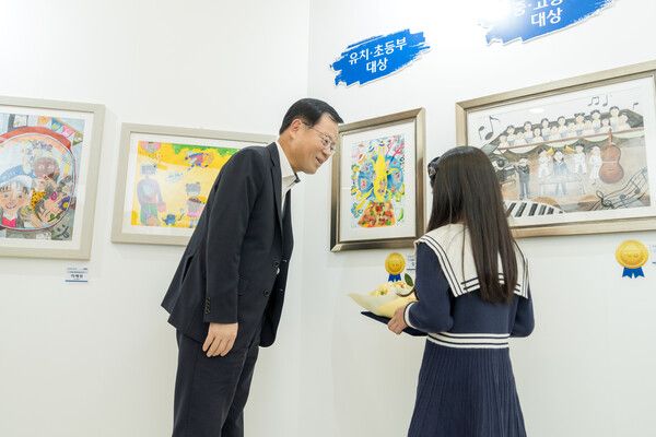 조병규 은행장이 지난 25일 제27회 ‘우리 아트콘’ 미술대회 수상자와 작품들에 대한 이야기를 나누고 있다. [우리은행]