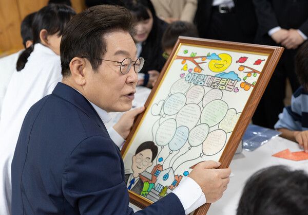 이재명&nbsp;대통령이 추석 연휴 3일 인천의 한 아동양육시설을 방문해 어린이들이 준비한 메시지가 적힌 액자를 살펴보고 있다. [연합뉴스]