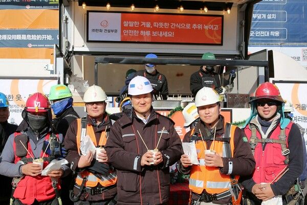 김우석 한화 건설부문 대표이사(가운데)가 건설현장 근로자들과 함께 ‘찾아가는 겨울간식차’의 호빵과 어묵을 즐기고 있다. [한화 건설부문]