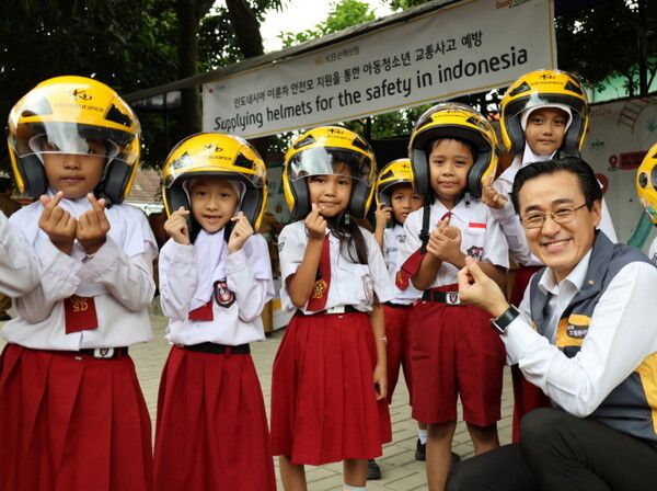 KB손해보험은 지난 11일, 인도네시아 자카르타 서부 지역에 위치한 발라라자(Balaraja) 초등학교에서 ‘이륜차 안전모 전달식’을 진행했다. 이날 안전모 전달식에 참여한 조정래 KB손해보험 인니법인장(맨 오른쪽)과 학생들이 손하트를 하며 기념사진을 찍고 있다. [KB손해보험]