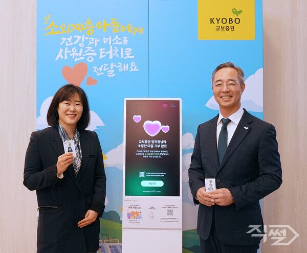 이석기 교보증권 대표이사(오른쪽)와 직원이 1일 교보증권 1층 기부 키오스크에 서 기념사진을 촬영하고 있다. [교보증권]