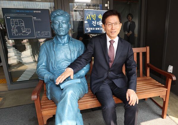 김문수 전 고용노동부 장관이 10일 서울 종로구 전태일기념관에 설치된 전태일 동상 옆에 앉아 있다. [이하 연합뉴스]