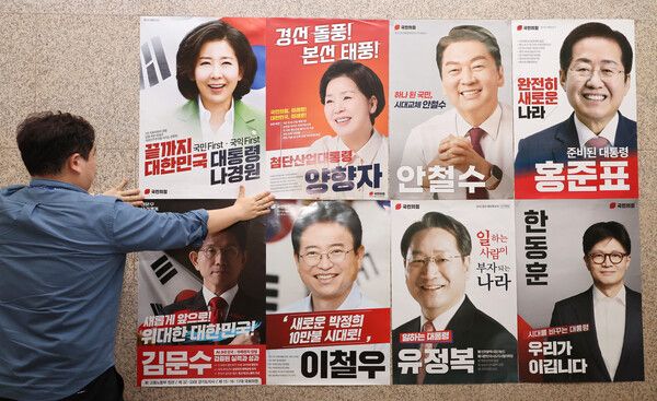 20일 서울 여의도 국회 본청 국민의힘 사무실 앞에 당 관계자가 대선 경선 후보자 포스터를 붙이고 있다. [연합뉴스]