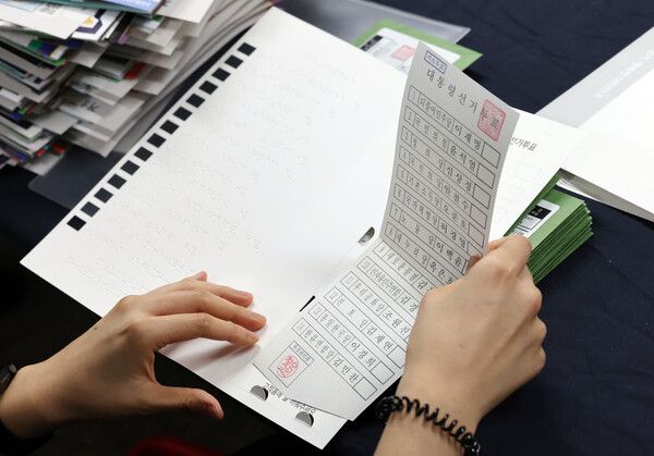 제20대 대통령선거를 앞둔 2022년 26일 서울시 용산구선거관리위원회에서 관계자들이 시각장애인을 위해 제작된 점자형 투표보조용구에 투표용지를 넣고 있다. [사진=연합뉴스]