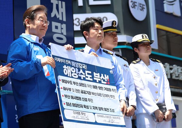 더불어민주당 이재명 대선 후보가 14일 부산 부산진구 서면 젊음의 거리에서 열린 유세에서 권기흥 에이치라인해운해상직원노조 위원장과 해양수도 부산 협약서에 서명한 후 기념 촬영하고 있다. [연합뉴스]