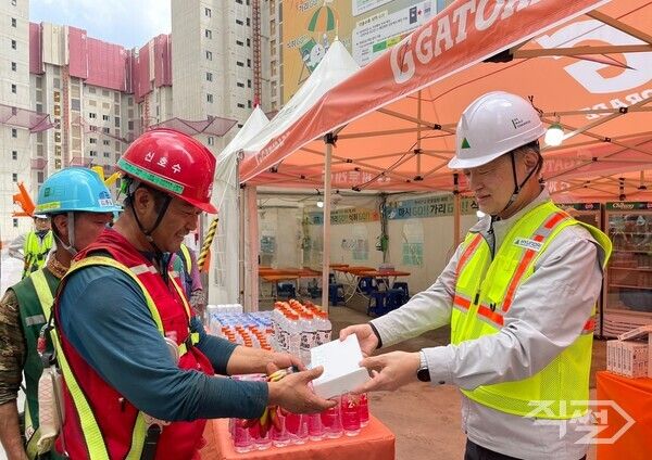 황준하 현대건설&nbsp;CSO(전무)가 21 근로자에게 수분 보충과 탈수 예방을 위한 이온음료와 쿨링스프레이를 직접 전달하고 있다. [현대건설]