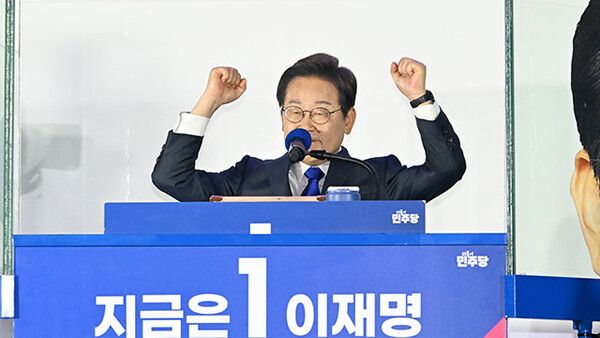 제21대 대통령 당선이 확실시되는 더불어민주당 이재명 대선 후보와 부인 김혜경 여사가 4일 서울 여의도 국회 인근에서 당 주최로 열린 국민개표방송 행사에 참석해 꽃다발을 받고서 시민들을 향해 두 팔을 들어올려 인사하고 있다. [KBS뉴스 갈무리]