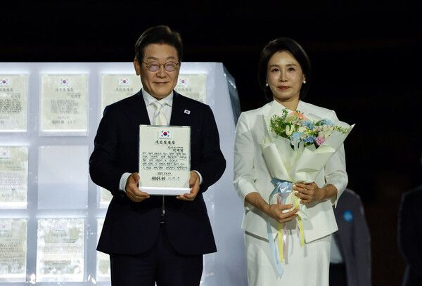 이재명 대통령과 김혜경 여사가 15일 서울 세종대로 광화문광장에서 열린 제21대 대통령 국민임명식 '광복 80년, 국민주권으로 미래를 세우다' 행사에서 국민 대표 80인으로부터 '빛의 임명장'을 받은 뒤 감사 인사를 하고 있다. [이하 연합뉴스]