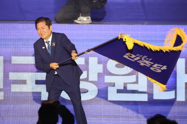 더불어민주당 정청래 신임 당대표가 2일 고양 킨텍스에서 열린 전국당원대회에서 김병기 당대표 직무대행 겸 원내대표로부터 받은 당기를 흔들고 있다. [연합뉴스]