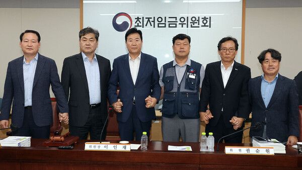 10일 정부세종청사에서 열린 제12차 전원회의에서 내년 최저임금을 시간당 1만320원으로 17년만에 합의로 결정한 공익위원-사용자위원-근로자위원들이 손을 잡고 기념촬영을 하고 있다. 왼쪽부터 하헌제 상임위원, 이인재 위원장, 사용자위원인 류기정 한국경영자총협회 전무, 근로자위원인 류기섭 한국노총 사무총장, 사용자위원인 이명로 중소기업중앙회 인력정책본부장, 공익위원인 권순원 숙명여대 교수. [연합뉴스]