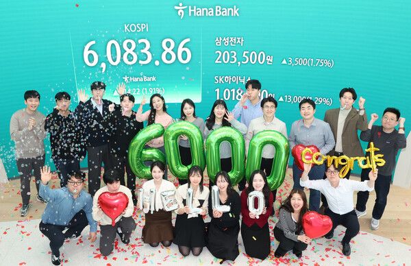 코스피가 사상 처음으로 6000을 돌파한 25일 서울 중구 하나은행 딜링룸에서 딜러들이 기념 세리머니를 하고 있다. [연합뉴스]