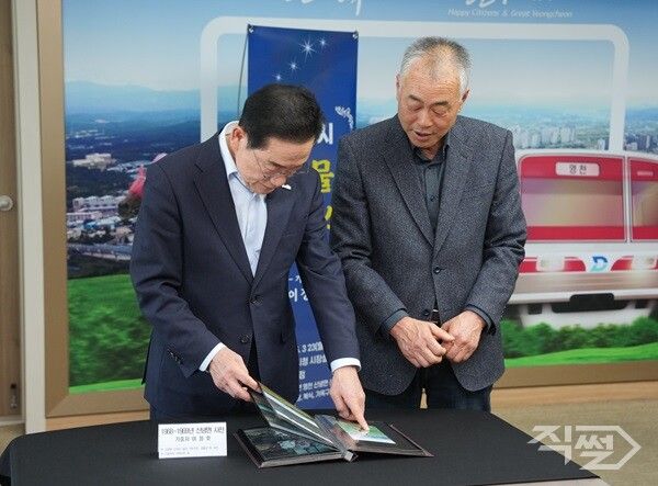 기증자가 영천시장에게 기증 사진에 대해 설명하고 있다. [영천시]