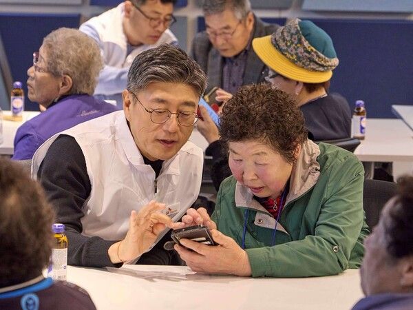 정재헌 SKT CEO(왼쪽)가 경기도 포천시 관인노인대학에서 어르신 고객의 스마트폰을 살펴보고 대화를 나누는 모습. [SKT]