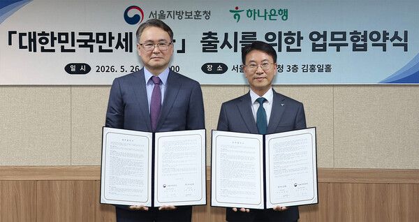 하나은행은 지난 26일 오후 서울 용산구 서울지방보훈청에서 호국보훈의 달을 맞아 ‘대한민국만세 적금’ 출시를 위한 업무협약을 체결했다. 이날 협약식에 참석한 김영호 하나은행 리테일그룹 그룹장(사진 오른쪽)이 이승우 서울보훈청장과 함께 협약서를 들고 기념촬영을 하고 있다. [하나은행]