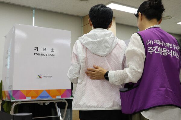 제9회 전국동시지방선거 사전투표 첫날인 29일 세종시 북세종통합행정복지센터에 마련된 투표소에서 한 장애인이 세종시장애인부모회 회원들의 활동보조를 받아 투표하고 있다. [연합뉴스]