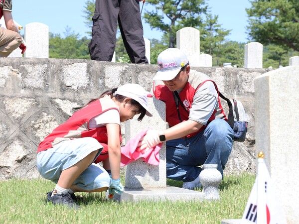 롯데건설 ‘샤롯데 봉사단’이 지난달 30일 서울 동작구에 위치한 국립서울현충원 20번 묘역에서 비석을 닦고 태극기를 꽂는 등 봉사활동을 하고 있다. [롯데건설]