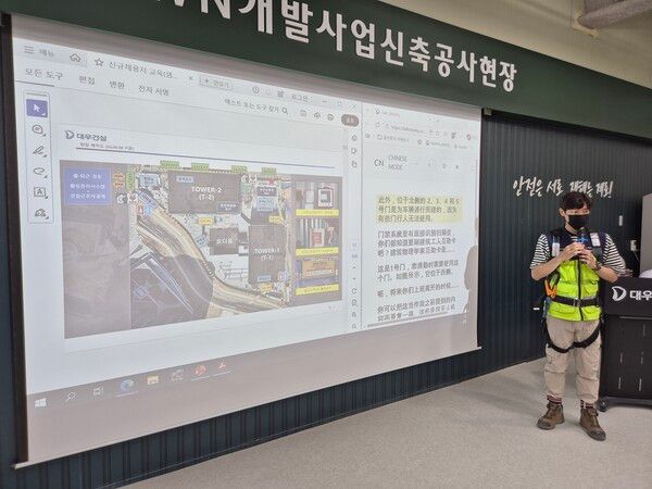 대우건설 관계자가 과천 G-TOWN 개발사업 신축공사 현장에서 외국인 근로자를 위한 AI 번역기 기능에 대해 교육하고 있다. [대우건설]
