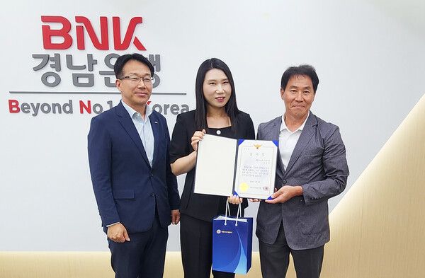 BNK경남은행&nbsp;소답동지점&nbsp;직원(사진&nbsp;가운데)이&nbsp;남인균&nbsp;창원서부경찰서&nbsp;형사지원팀&nbsp;팀장(사진&nbsp;오른쪽)으로부터&nbsp;감사장을&nbsp;받은&nbsp;뒤&nbsp;기념촬영을&nbsp;하고&nbsp;있다. [BNK경남은행]