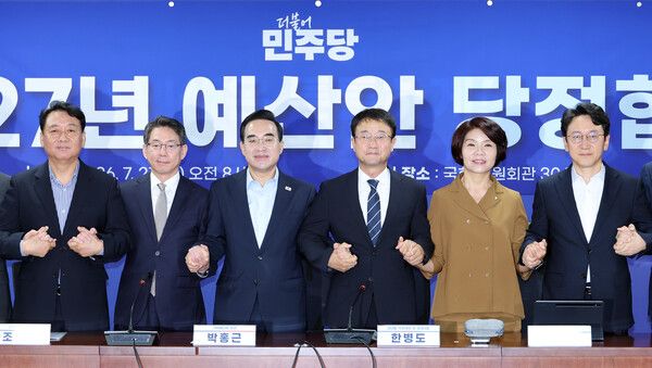 더불어민주당 한병도 직무대행 겸 원내대표와 박홍근 기획예산처 장관이 21일 국회 의원회관에서 열린 2027년 예산안 당정 협의에서 손을 잡고 기념 촬영을 하고 있다. 왼쪽부터 이광재 예결위원장, 기획예산처 조용범 차관, 박홍근 장관, 더불어민주당 한병도 대표 직무대행 겸 원내대표, 한정애 정책위의장, 천준호 원내운영수석부대표. [연합뉴스]