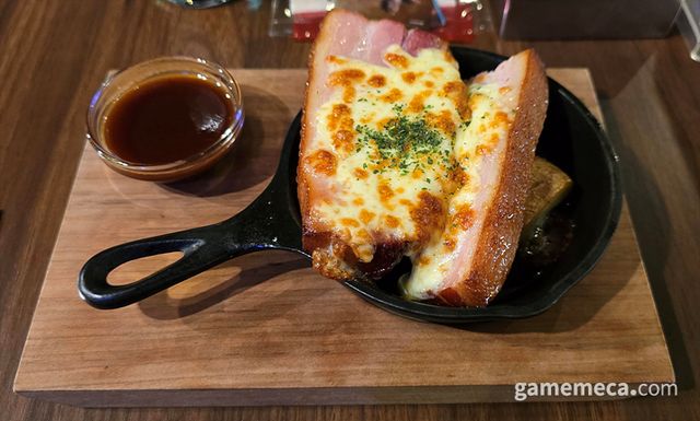 다음으로 나온 것은 조사단의 직화요리다. 두툼한 베이컨과 크게 썬 감자, 구운 치즈와 BBQ 소스로 구성됐다 (사진: 게임메카 촬영)