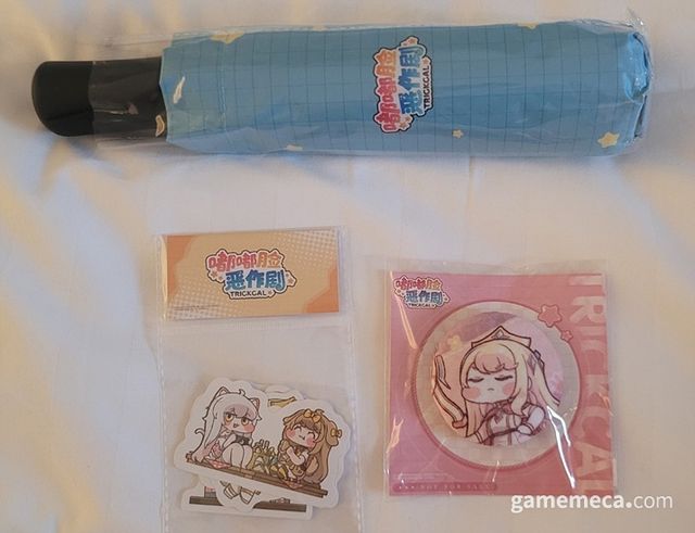 트릭컬 특유의 따스한 동화감성 배색이 인상 깊은 굿즈들. 참고로 에르핀 뱃지는 쿠션 재질로, 누를 때마다 폭신한 느낌이 든다고 (사진: 게임메카 촬영)