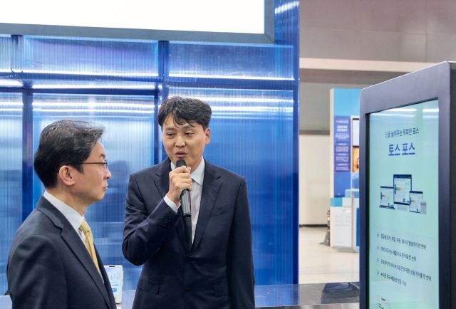 ‘코리아 핀테크 위크 2025’ 토스 부스에서 비바리퍼블리카 이승건 대표(오른쪽)가 이억원 금융위원장(왼쪽)에게 ‘토스 포스’를 설명하는 모습 / 사진 제공=비바리퍼블리카