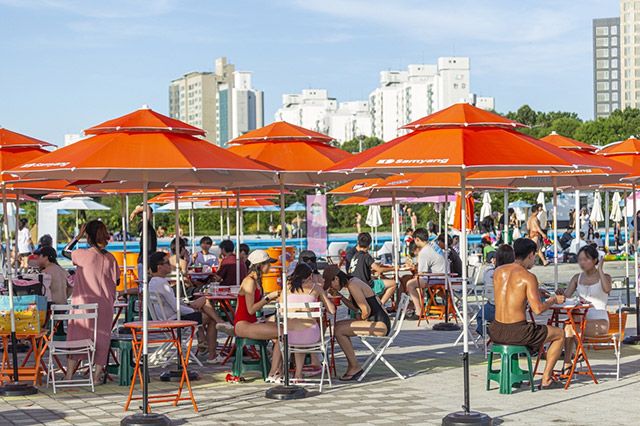 삼양식품 파라솔이 설치된 공간에서 시민들이 라면을 먹으며 휴식을 취하고 있다./ 사진= 삼양식품
