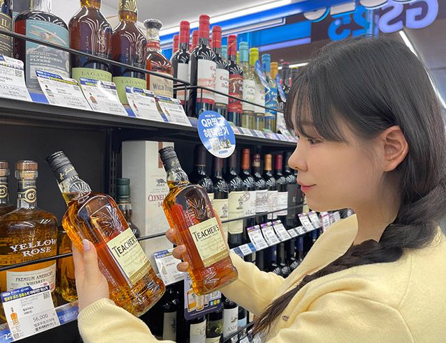 GS25에서 모델이 가성비 위스키 티처스를 살펴보고 있다./GS25