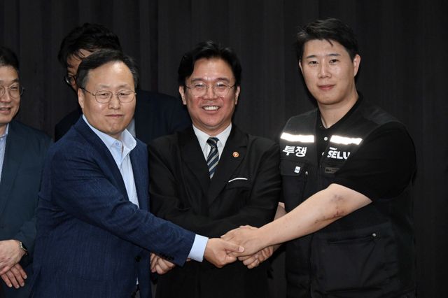 20일 경기도 수원시 장안구 경기고용노동청에서 열린 삼성전자 임금협상을 마친 후 여명구 삼성전자 DS(디바이스솔루션·반도체 사업 담당) 피플팀장과 김영훈 고용노동부 장관, 최승호 삼성그룹 초기업노동조합 삼성전자지부 위원장이 잠정 합의한에 서명한 후 손을 맞잡고 있다./뉴스1