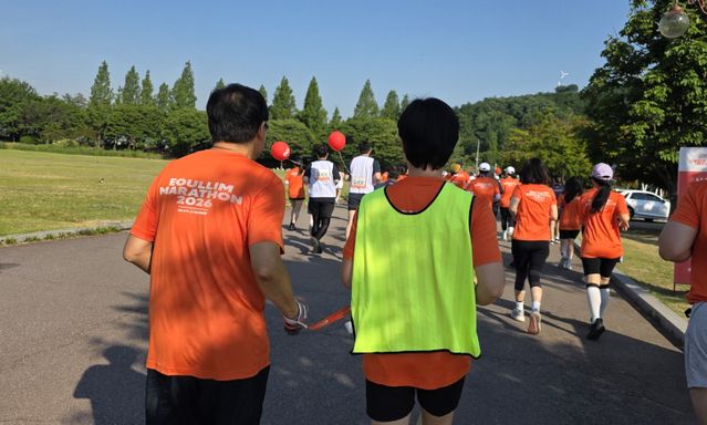 시각장애인 참가자와 가이드 러너들이 손목의 가이드 끈으로 연결된 채 함께 코스를 달리고 있다./김경희 기자