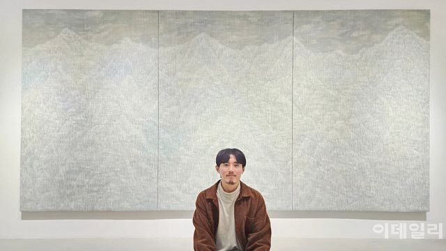 작가 우병윤이 선화랑 개인전 ‘중첩: 들떠 있는 풍경’에 건 동명의 작품 ‘중첩: 들떠 있는 풍경 26-09-330’(2026) 앞에 앉았다. 바닥에 앉아보자는 제안에 작가는 잠시의 망설임도 없었다. 120호 규모(194.0×130.3㎝) 화폭 3점을 연결한 이 대작은 수만 번 베고 갔을 그 칼끝에 남은 선과 선이 웅장한 산수를 빚고 있다. 도려낸 만큼 선명해지는 풍경이다(사진=오현주 문화전문기자).