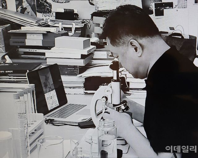 작가 이이남이 담양 용소폭포에서 건져낸 한 방울 물을 현미경으로 들여다보고 있다. 이번 개인전에 내놓은 전시작들이 세상에 나오는 시작점이 된 작업이다. 갤러리가 준비한 작가 작업 영상 중 한 장면이다(사진=학고재갤러리·오현주 문화전문기자).