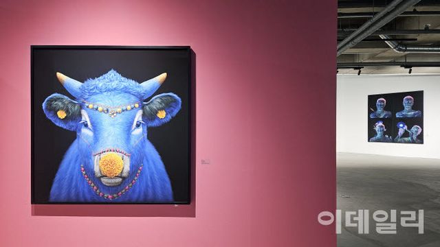고상우 개인전 ‘너와 함께 쉬는 숨’ 전경. 앞쪽으로 ‘카마데누’(Kamadhenu, 2026, 150×150㎝·앞)가 내걸렸다. 코와 귀, 머리와 목에 달고 매단 꽃과 장신구는 세상을 대신해 전한 작가의 ‘미안한 마음’이다. 멀리 뒤로 작가의 ‘자화상’ 연작(2026)이 보인다(사진=오현주 문화전문기자).