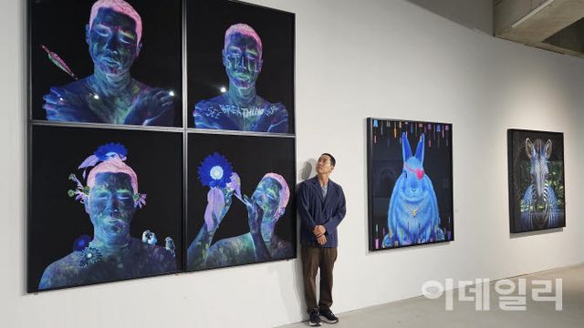 작가 고상우가 사비나미술관 개인전 ‘너와 함께 쉬는 숨’에 내건, 4점으로 제작한 ‘자화상’ 연작을 올려다보고 있다. “상처 입은 동물의 고통을 느끼려 천연기념물인 황새의 깃털을 몸에 박았다”는 ‘화살’(Arrow, 2026, 122×122㎝·위 왼쪽)부터 ‘나는 여전히 숨 쉬고 있다’(I Am Still Breathing, 2026, 122×122㎝), ‘나는 다른 무언가로 변모한다’(Still Becoming; I Transform to Something Else, 2026, 122×122㎝), ‘감각의 향연: 나는 지금 당신과 함께 숨 쉬고 있다’(Celebration of the Senses; I Am Now Breathing with You, 2026, 122×122㎝)(사진=오현주 문화전문기자).