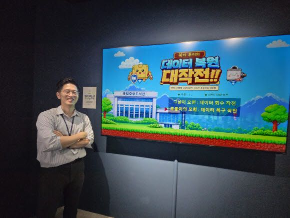 이연수 학예연구사가 AI 프로그램 등을 이용해 복원한 게임 앞에서 기념촬영을 하고 있다(사진=이윤정 기자).