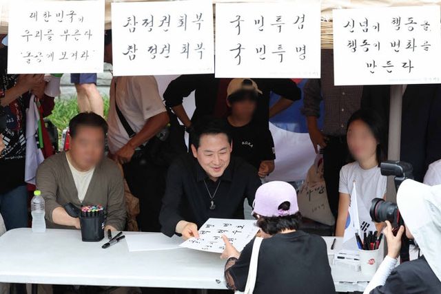 6·3지방선거 투표용지 부족 사태로 촉발된 잠실 개표소 봉쇄 시위가 이어진 17일 국민의힘 장동혁 대표가 서울 송파구 올림픽공원 핸드볼경기장 앞에서 집회 참가자들에게 붓글씨를 선물하고 있다.(사진= 연합뉴스)