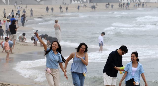 해운대해수욕장을 찾은 외국인 관광객들이 해변을 거닐며 활짝 웃고 있다. (사진=뉴스1)