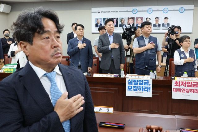 7일 정부세종청사 최저임금위원회에서 열린 제12차 전원회의에서 권순원 위원장과 근로자·사용자 위원들이 국기에 경례하고 있다.(사진=연합뉴스)