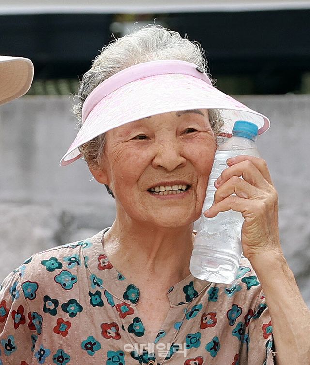 [이데일리 방인권 기자] 서울에 첫 ‘폭염중대경보’가 발령된 4일 서울 용산구 효창동 일대 골목에서 폐지를 수집하는 한 노인이 자원봉사자들이 건내준 생수를 얼굴에 대며 밝게 웃고 있다.