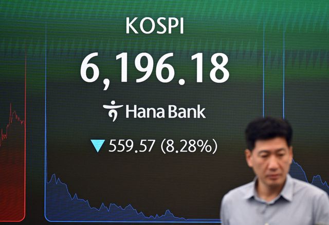 지난달 28일 서울 하나은행 본점 딜링룸에서 딜러가 코스피 지수가 표시된 전광판 앞을 지나고 있다. (사진=AFP)