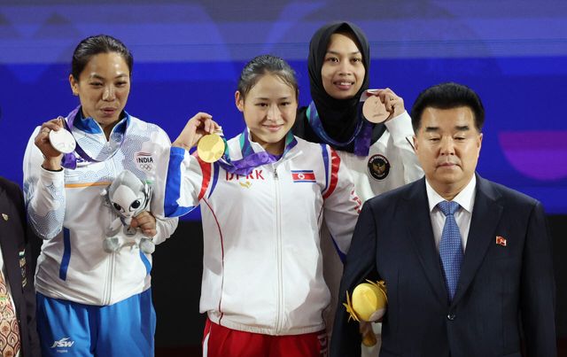 23일 일본 나고야 중소기업진흥회관에서 열린 2026 아이치·나고야 아시안게임 역도 여자 49㎏ 결승에서 금메달을 획득한 북한 리성금이 시상대에 올라 김일국 북한 체육상과 기념촬영을 하고 있다. 리성금은 인상 2차 시기 94kg, 용상 2차 시기 121kg를 성공하며 총합 215kg으로 금메달을 획득했다.(사진=연합뉴스)