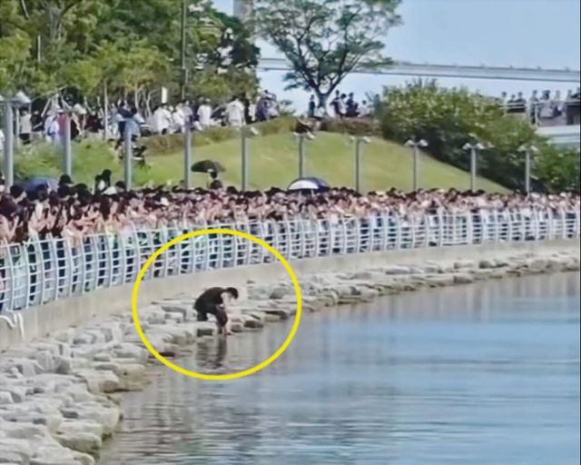 물에 빠진 휴대전화를 건지기 위해 부산 북항 친수공원 수로 난간을 넘어 내려간 시민의 모습. (사진=SNS 갈무리)